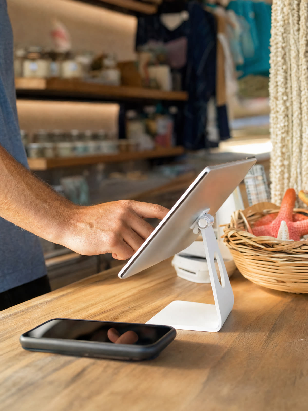 A hand tapping a tablet on the counter of a beach town shop